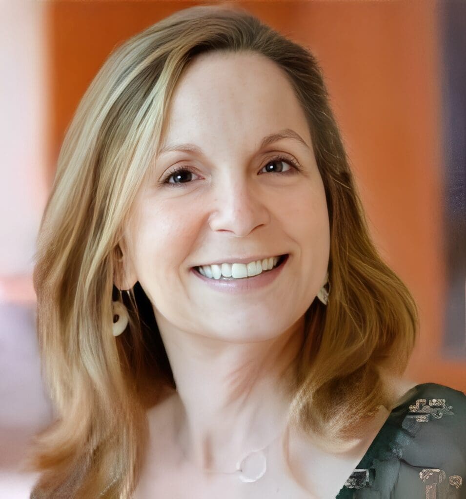 Smiling woman with blonde hair and earrings.
