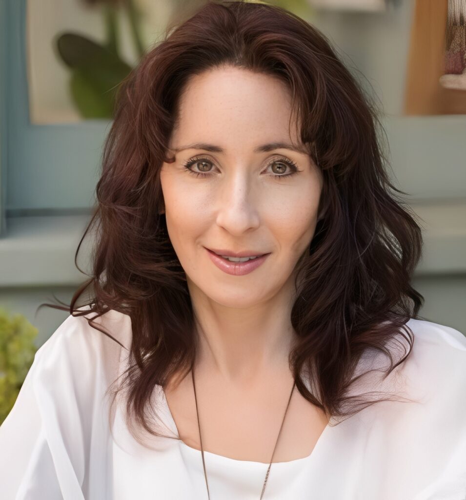 Smiling woman with brown hair outdoors.